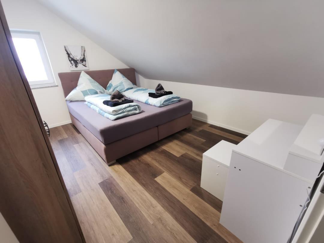 Schlafzimmer mit Doppelbett, Holzboden und Fenster unter Dachschrägen.