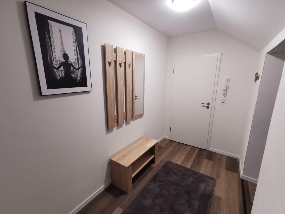 Eingangsbereich mit Holzbank, Wandspiegel und Bild an der Wand.