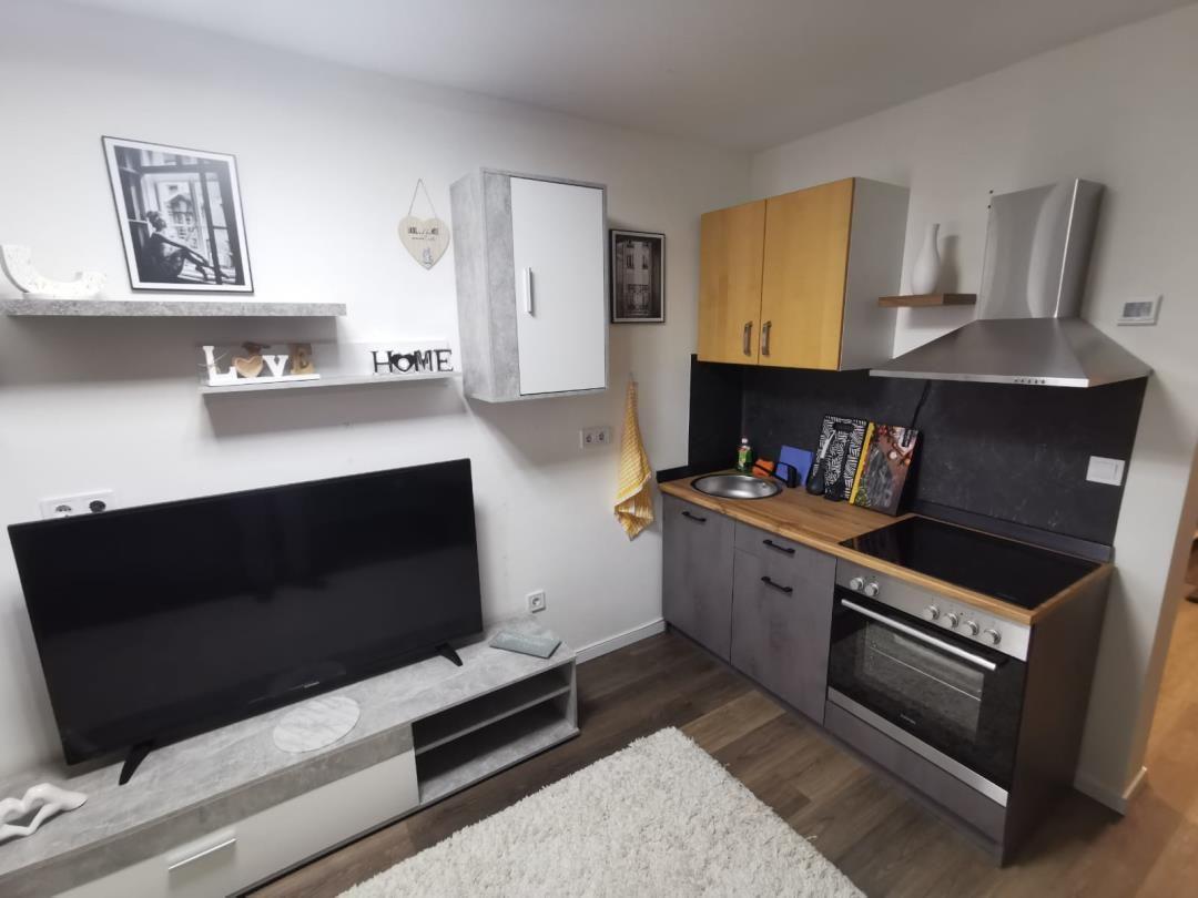 Wohnküche mit TV, Kochfeld und Schränken.