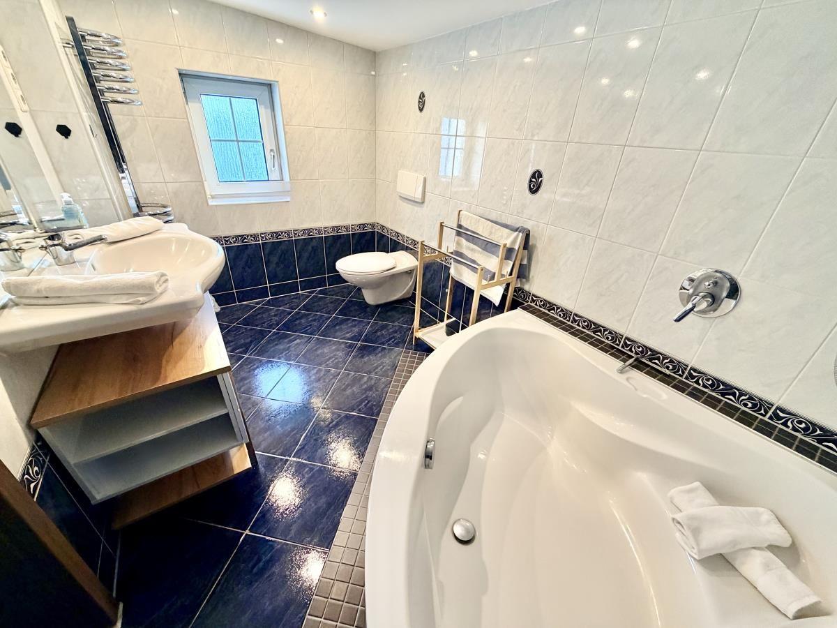 Badezimmer mit Badewanne, Waschbecken und Toilette. Fliesenboden und Wandfliesen.