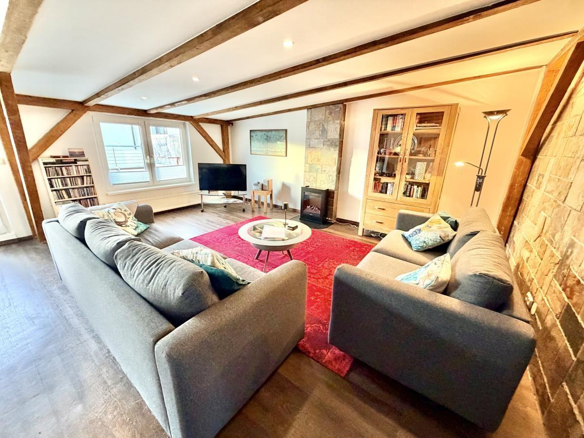 Wohnzimmer mit zwei Sofas, rotem Teppich und Holzbalken an der Decke.