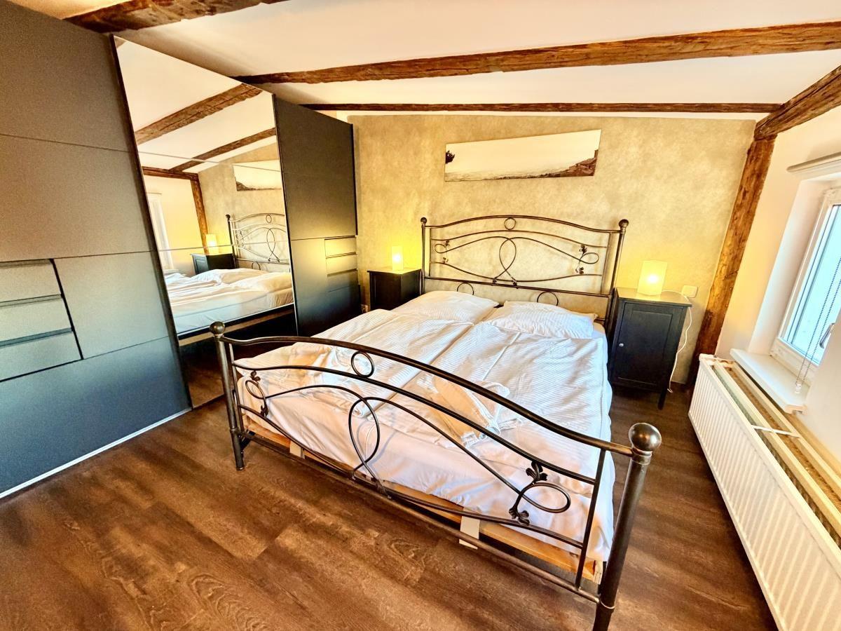 Schlafzimmer mit Doppelbett, Holzboden und Deckenbalken. Zwei Nachttische mit Lampen.