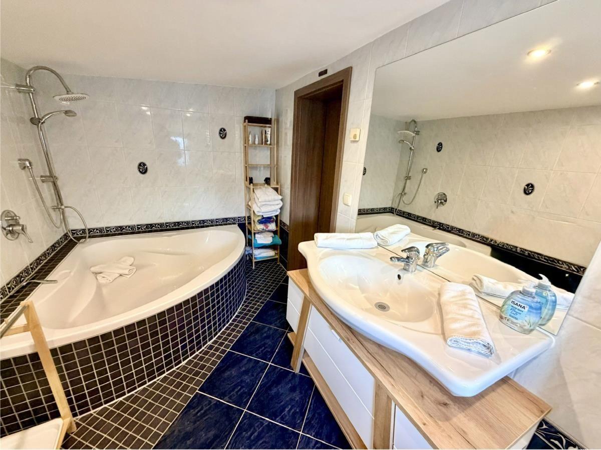 Badezimmer mit Badewanne, Dusche und Waschbecken mit Spiegel.