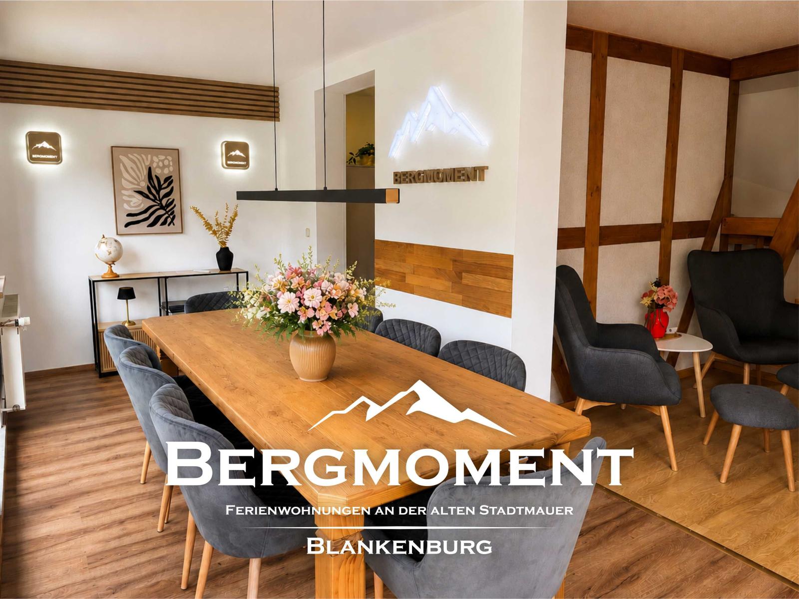 Esszimmer mit Holztisch, grauen Stühlen und Blumenarrangement. Wanddekoration und Holzverkleidung.