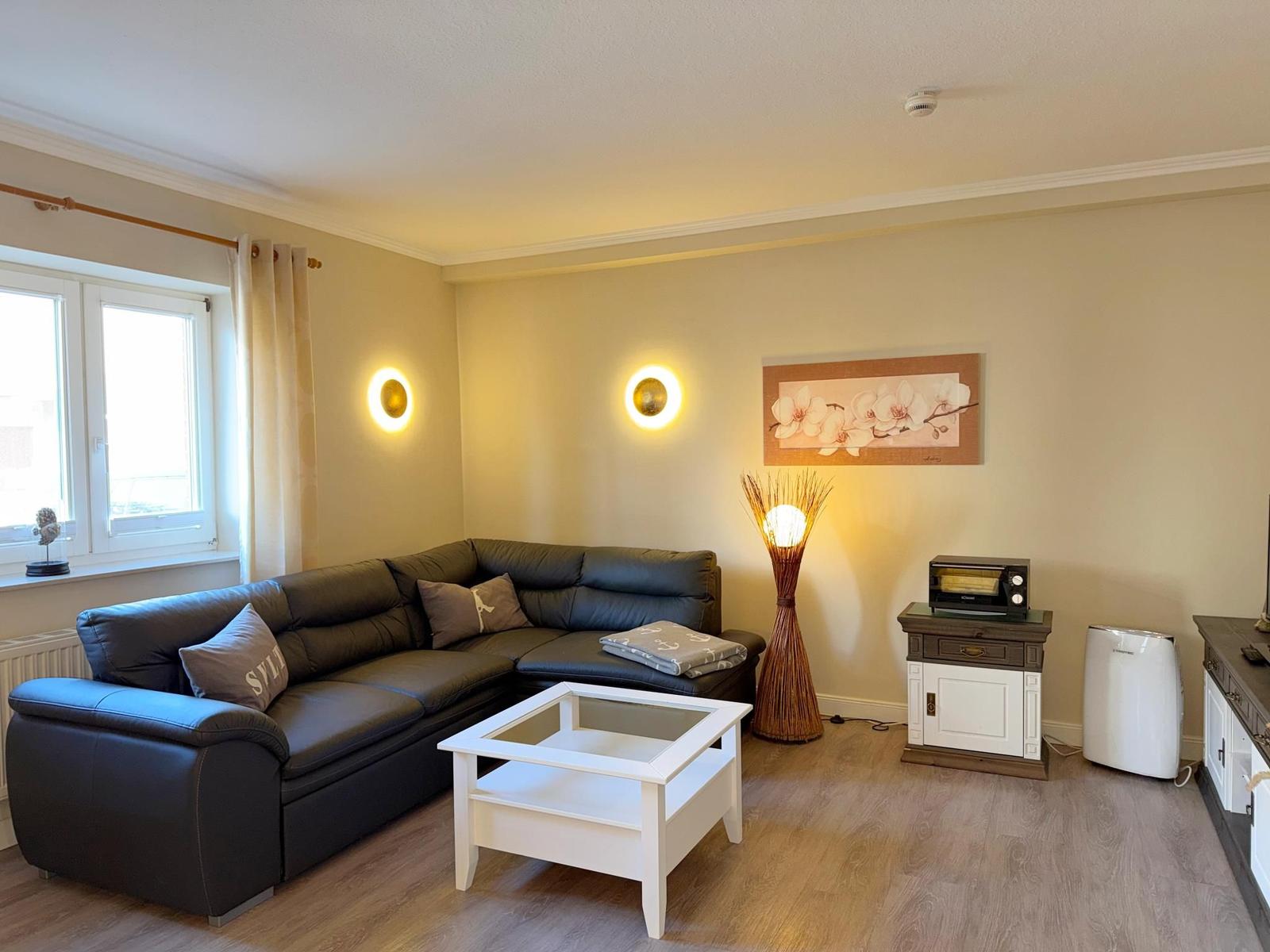 Ein Wohnzimmer mit einem schwarzen Sofa, einem weißen Tisch und einer Lampe.