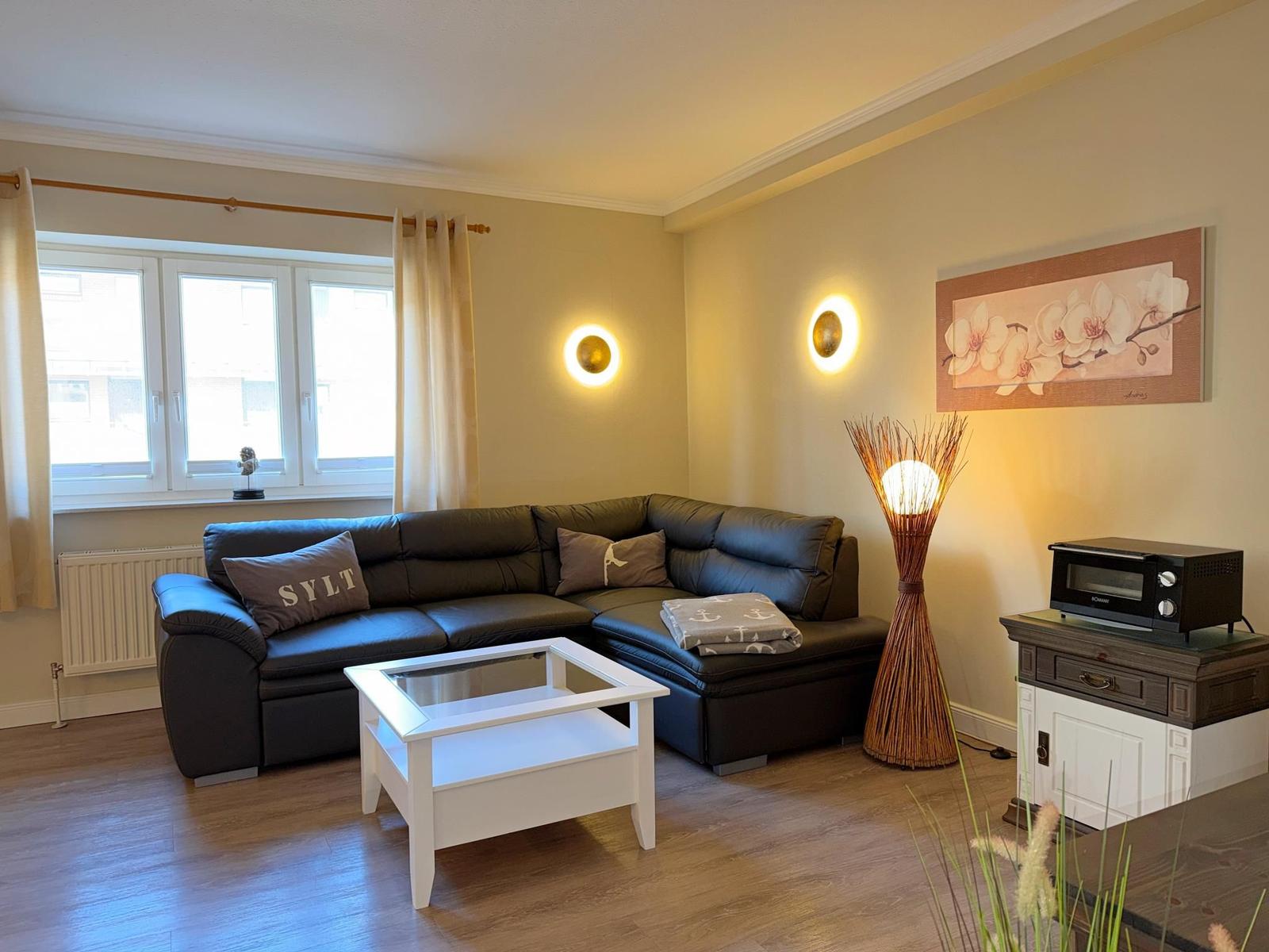 Wohnzimmer mit dunklem Sofa, weißem Tisch und Wandbild mit Orchideen.