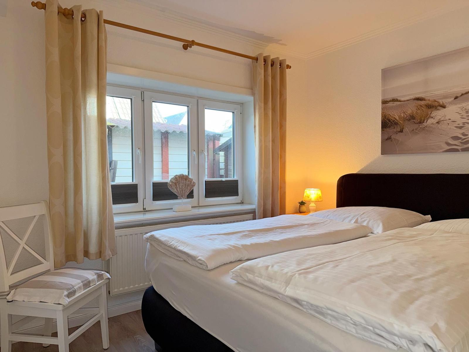 Ein Schlafzimmer mit Doppelbett, Fenster und Wandbild