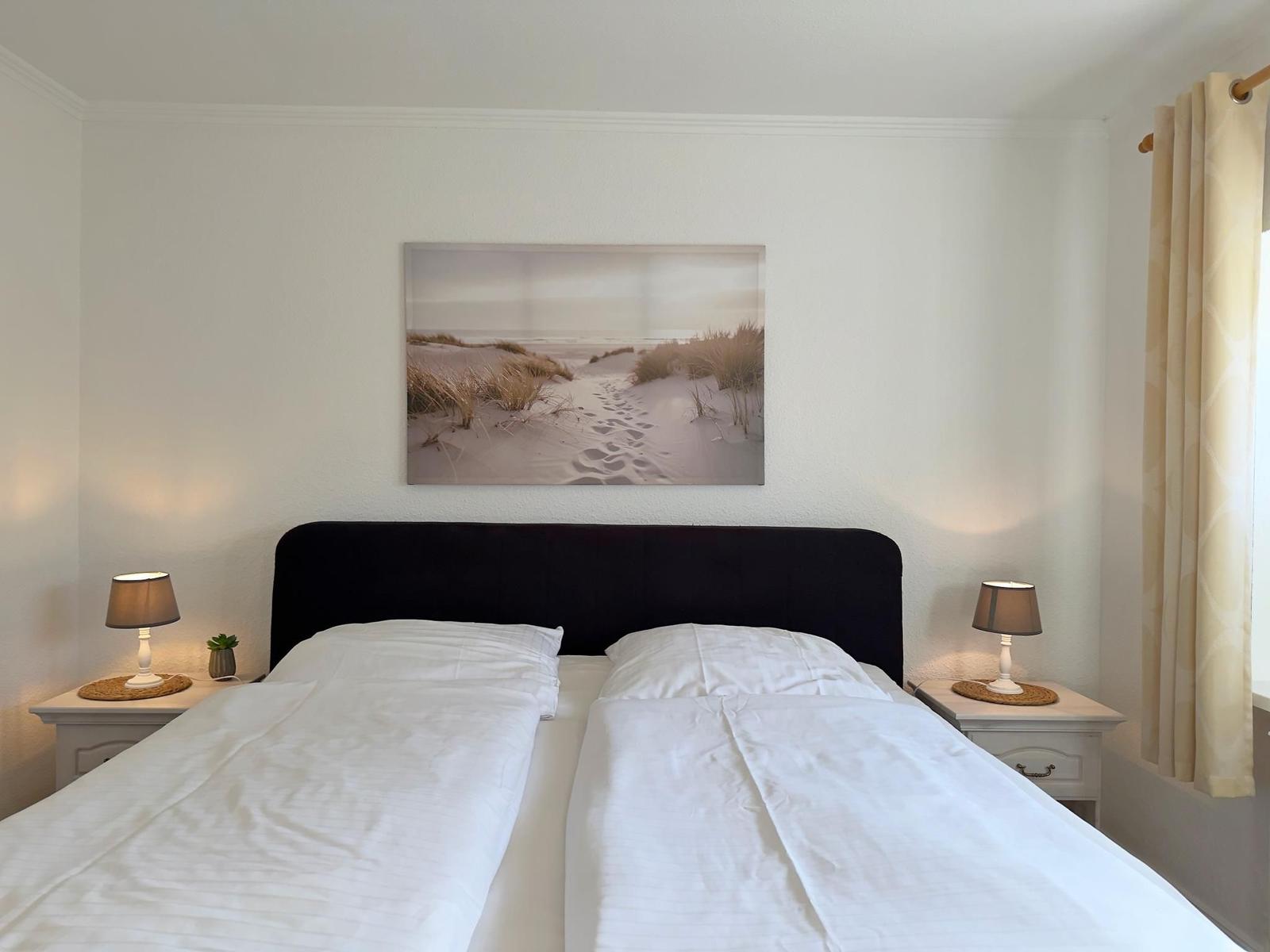 Schlafzimmer mit Doppelbett, zwei Nachttischen und Wandbild.
