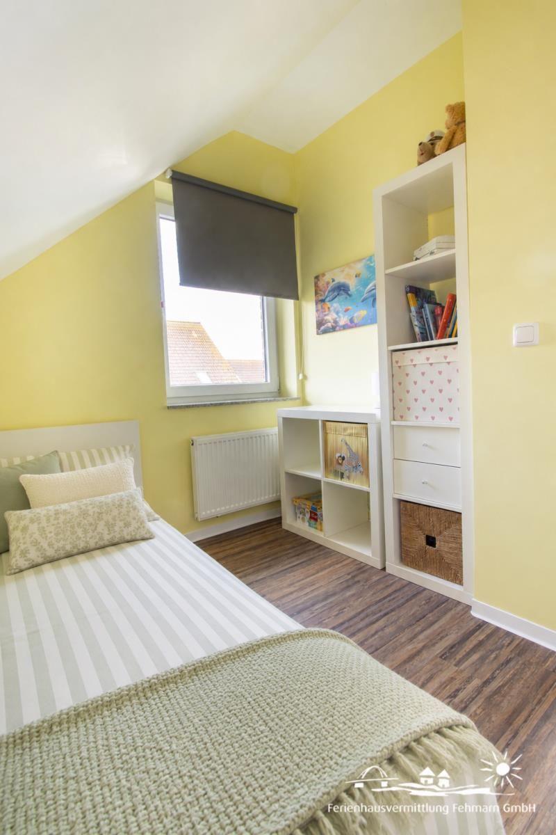 Bedroom with bed, cabinet, and window. Walls yellow, floor wood.