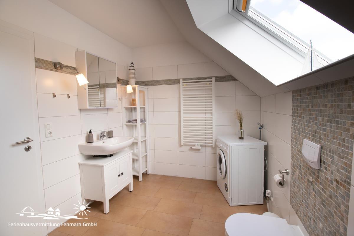 Bathroom with washing machine, toilet, and skylight.