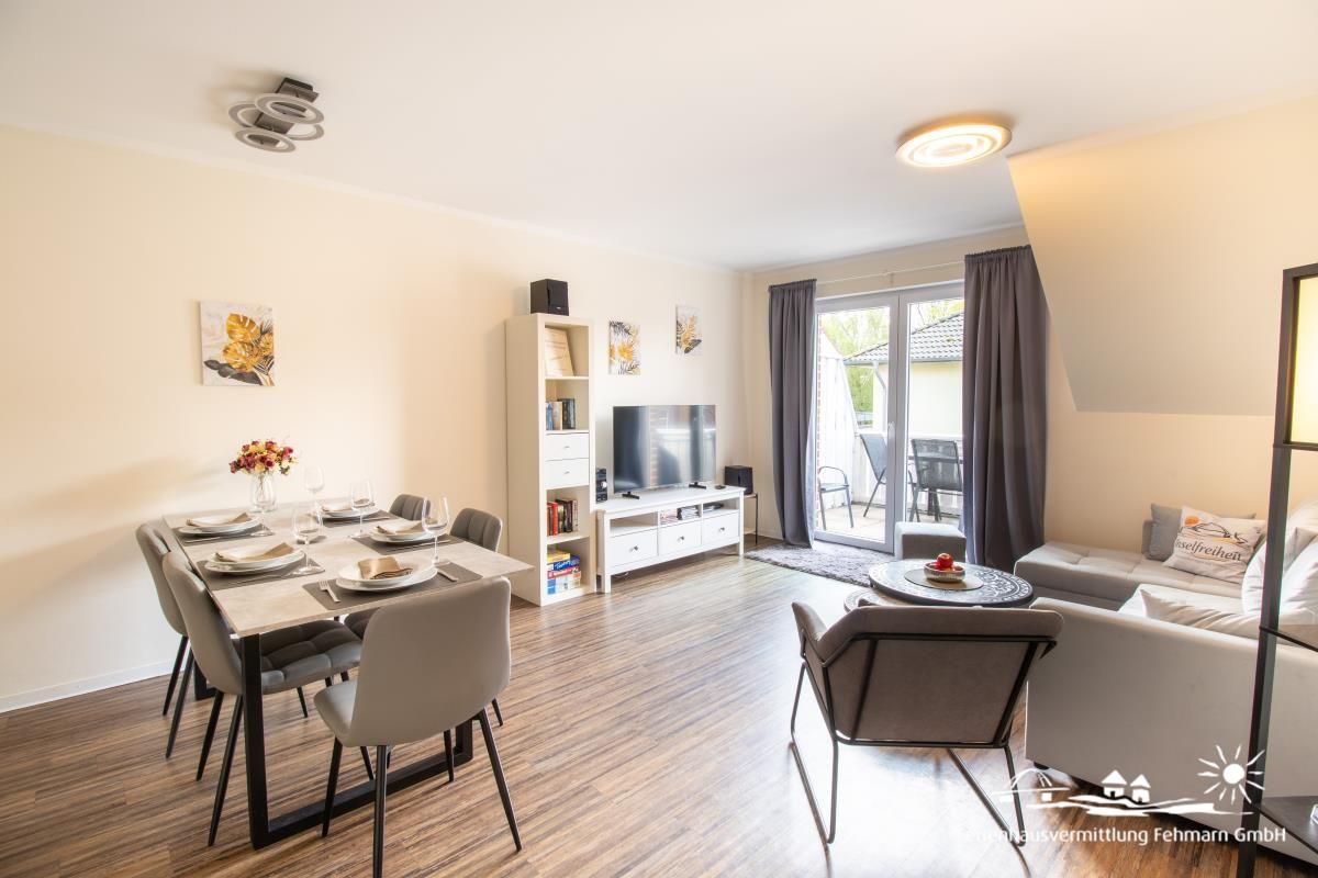 Living and dining area with TV, dining table, and view of the terrace.