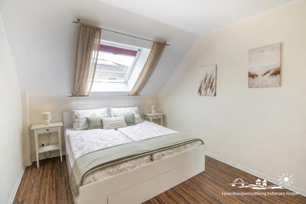Bedroom with sloped ceiling, double bed, two nightstands, and skylight.