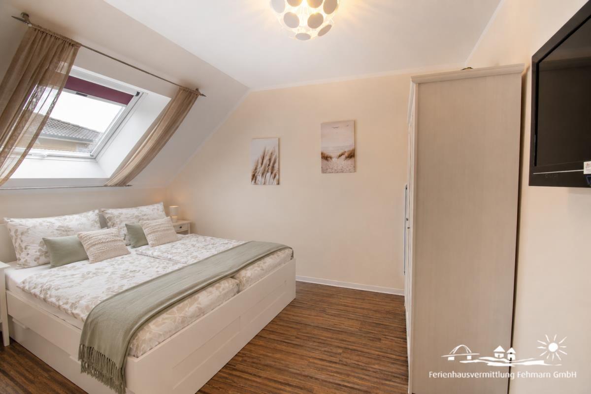 Bedroom with sloped ceiling, skylight, bed, and wardrobe.