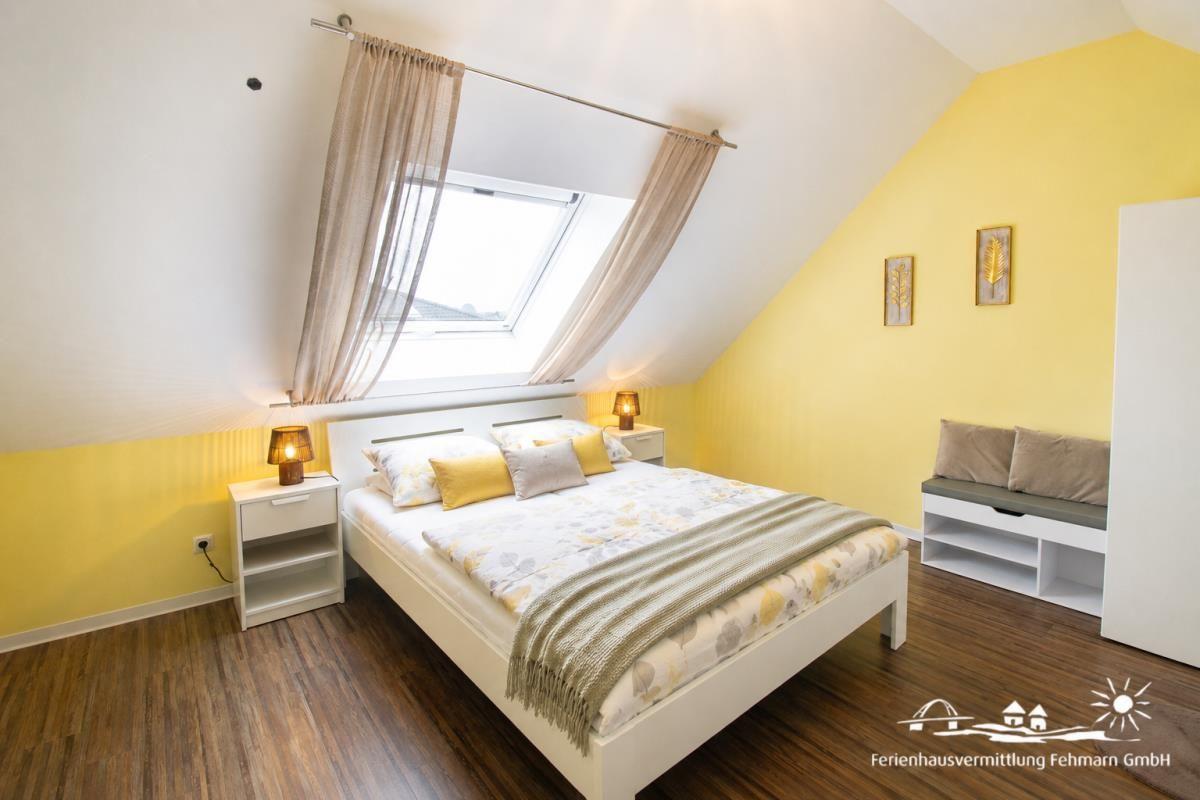 Bedroom with sloped ceiling, skylight, bed, and nightstands.