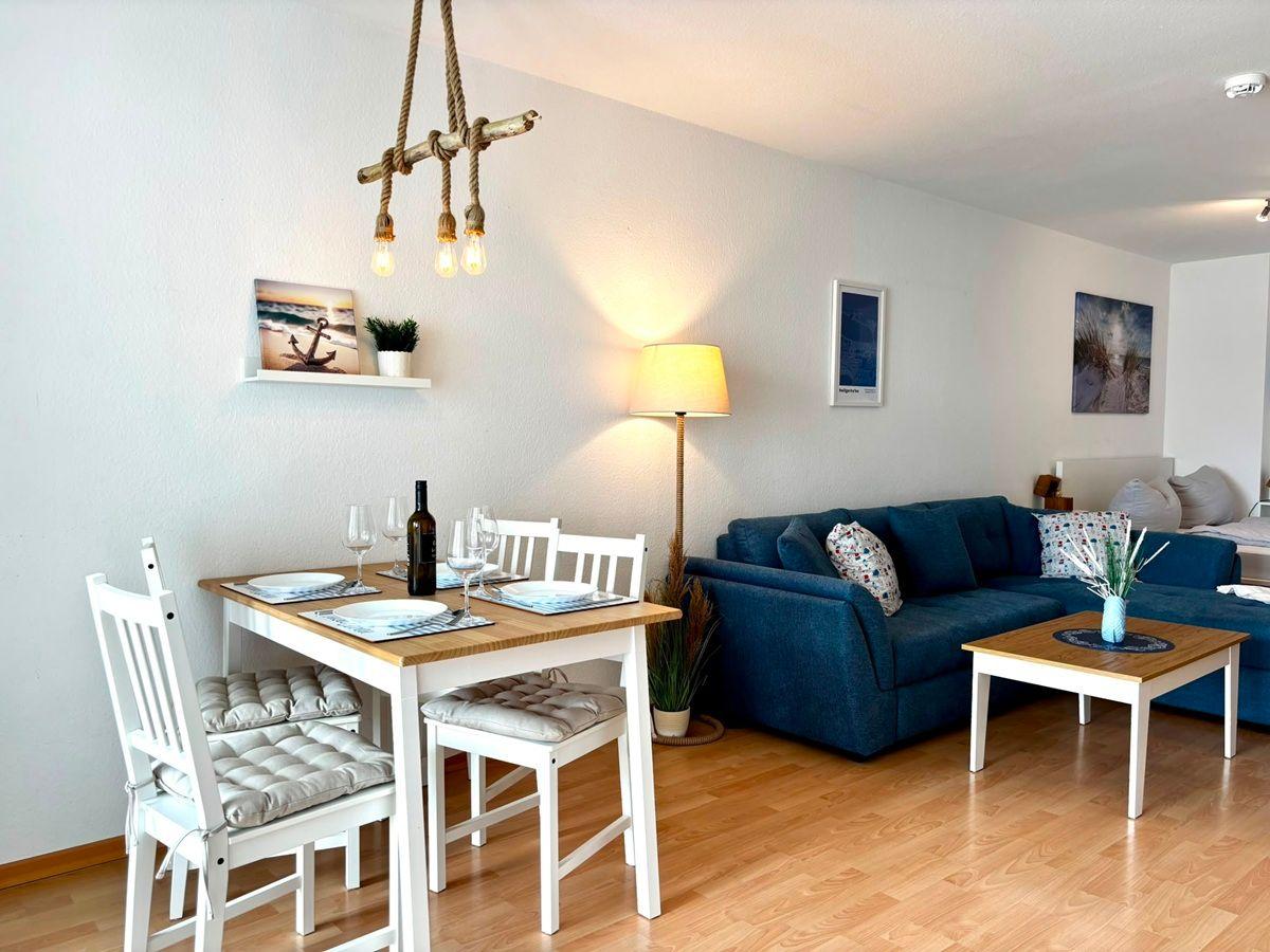 Essbereich mit Tisch und Stühlen, Wohnbereich mit Sofa und Couchtisch.