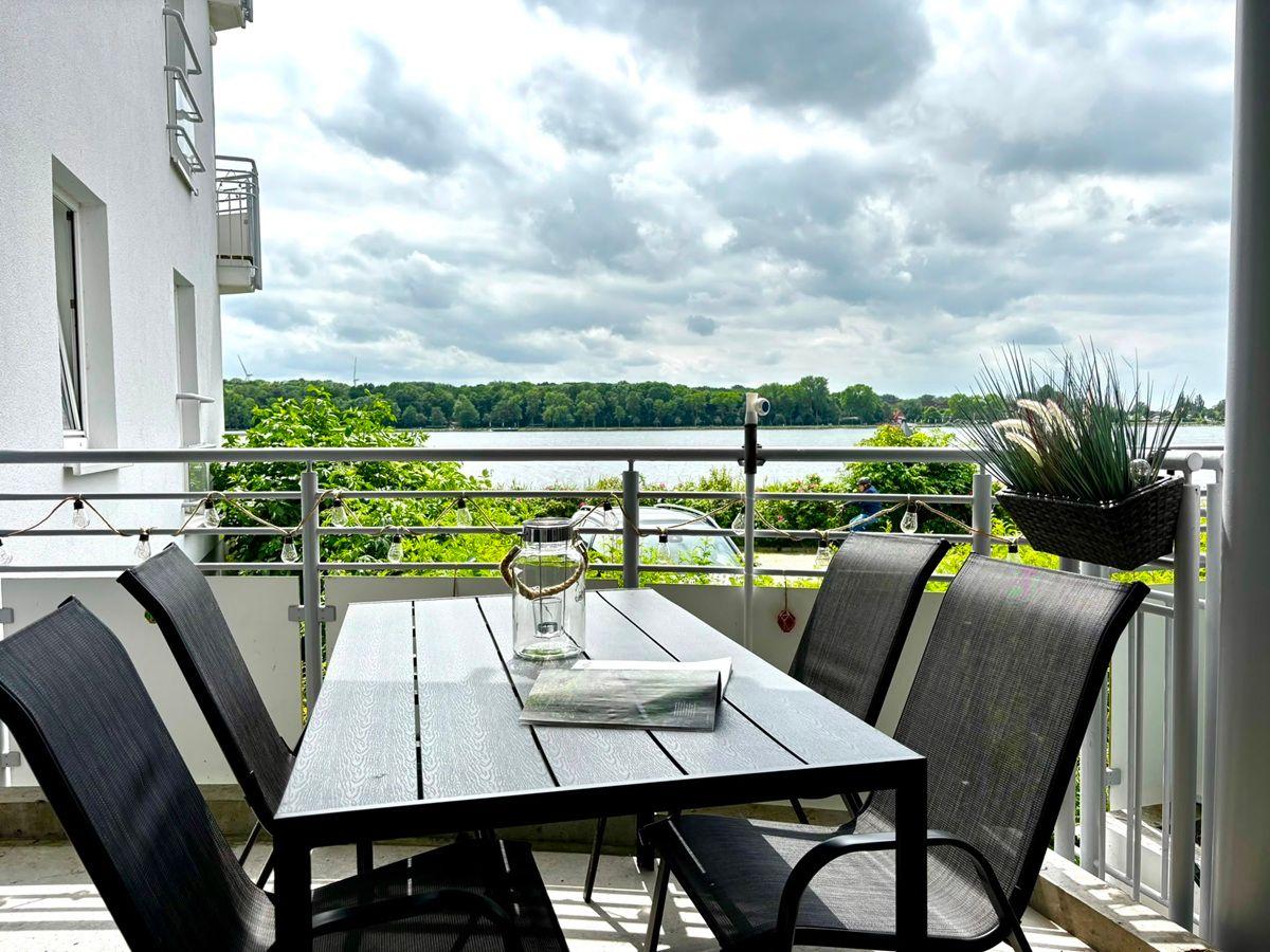 Terrasse mit Tisch und Stühlen, Blick auf Fluss und Bäume.