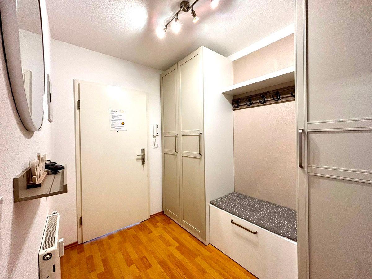 Eingangsbereich mit Schuhschrank, Garderobe und Spiegel an der Wand.