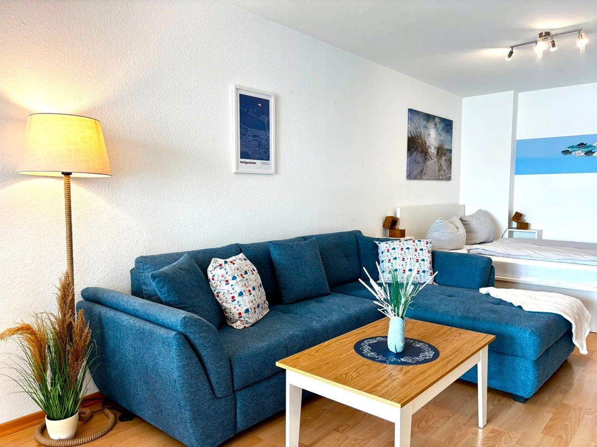 Ein Wohnzimmer mit blauem Sofa, Holztisch und Wandbildern.