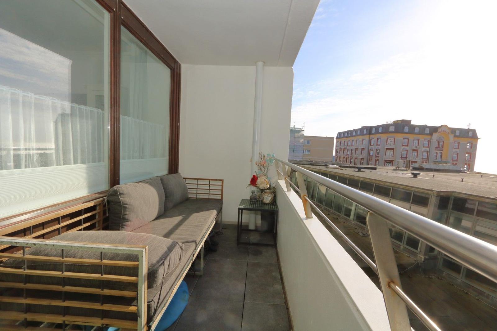 Balcony with bench, table, and view of buildings