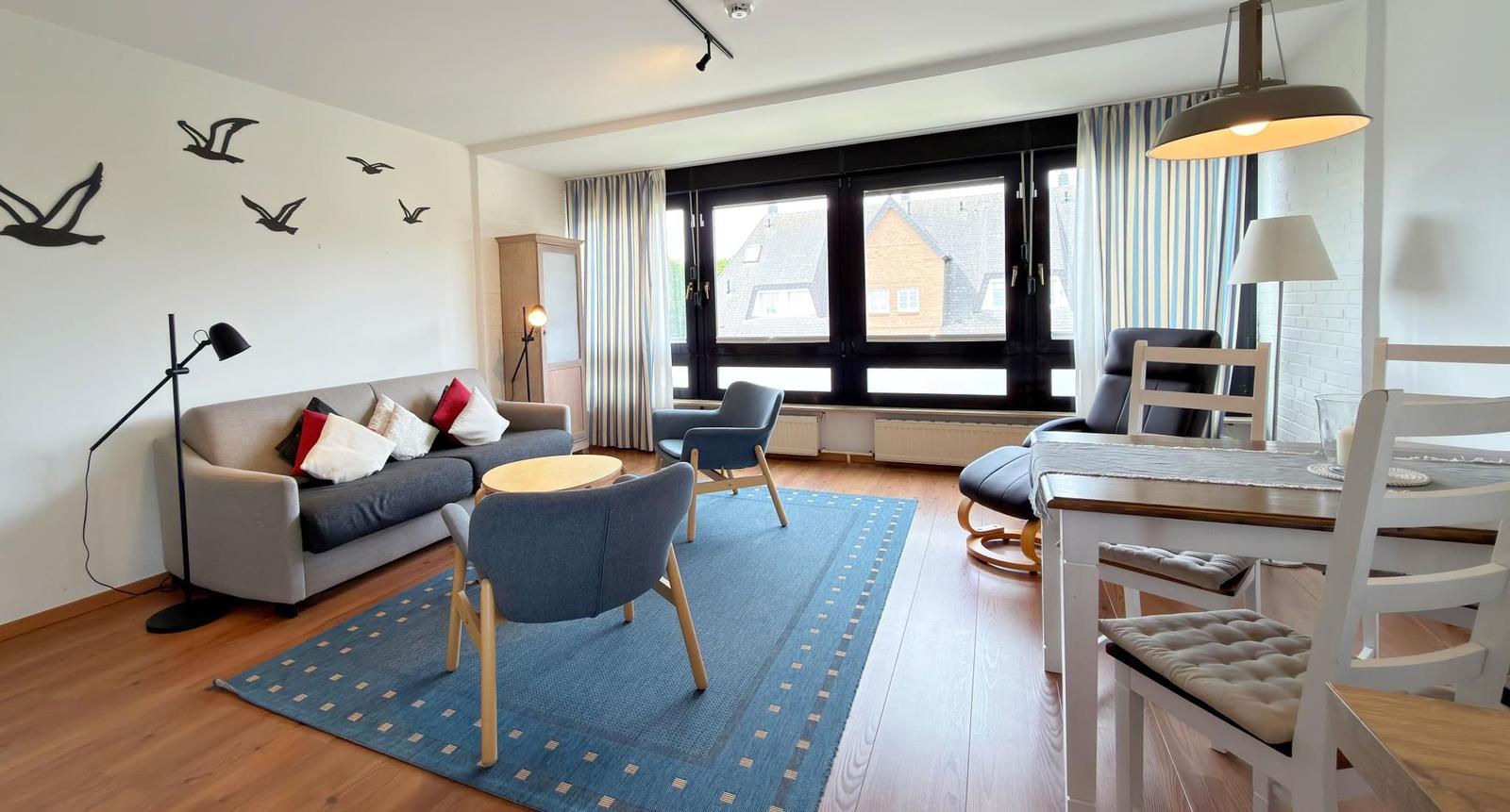 Wohn- und Essbereich mit Sofa, Stühlen und Fensterblick.