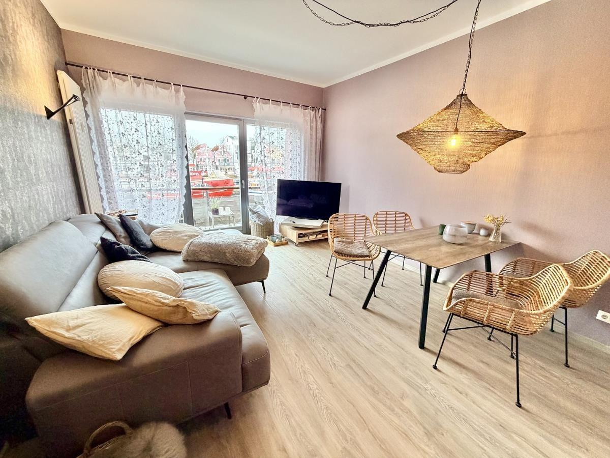 Wohn- und Essbereich mit Sofa, Esstisch und Blick auf Hafen.