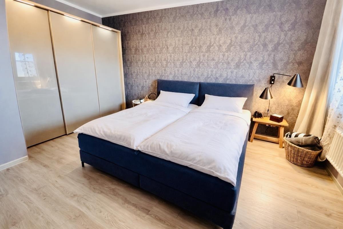 Schlafzimmer mit Doppelbett, Schwebetüren und Nachttisch mit Lampe.