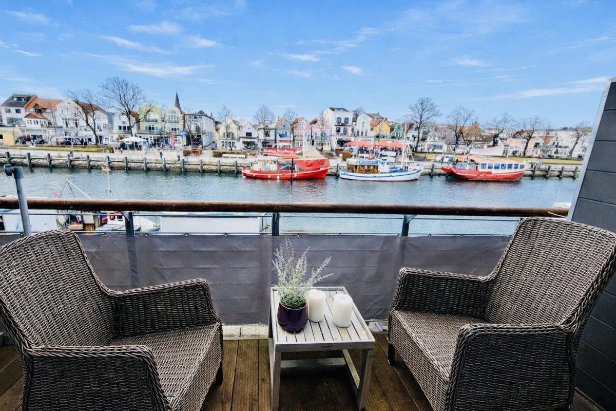 Terrasse mit zwei Stühlen und Tisch, Blick auf Hafen mit Booten und Häusern.