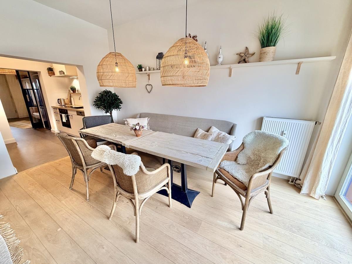 Esszimmer mit Tisch, Stühlen und Sofa an der Wand.