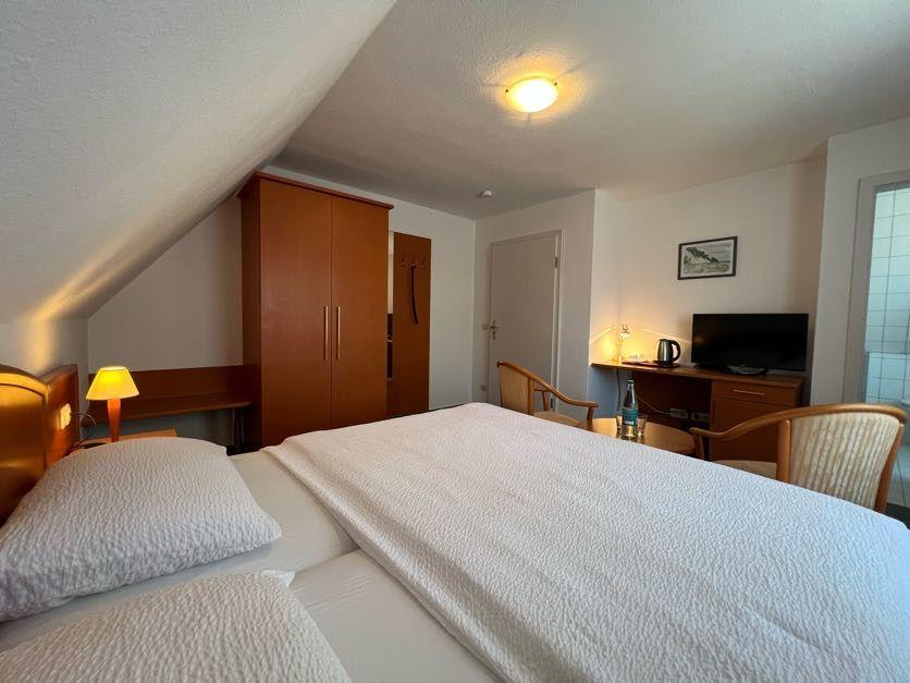 Ein Schlafzimmer mit Dachschrägen, Bett, Kleiderschrank und Fernseher.