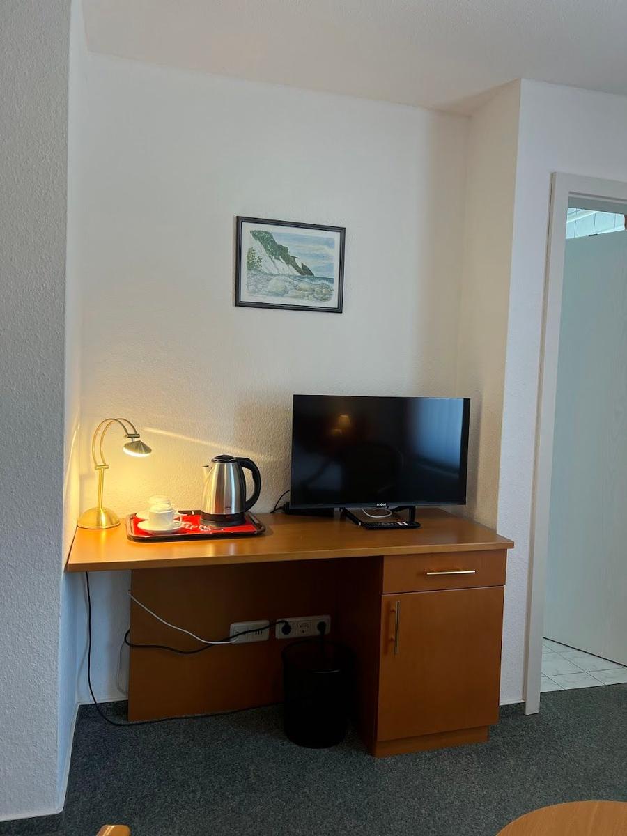 Schreibtisch mit Fernseher, Kaffeemaschine und Bild an der Wand.