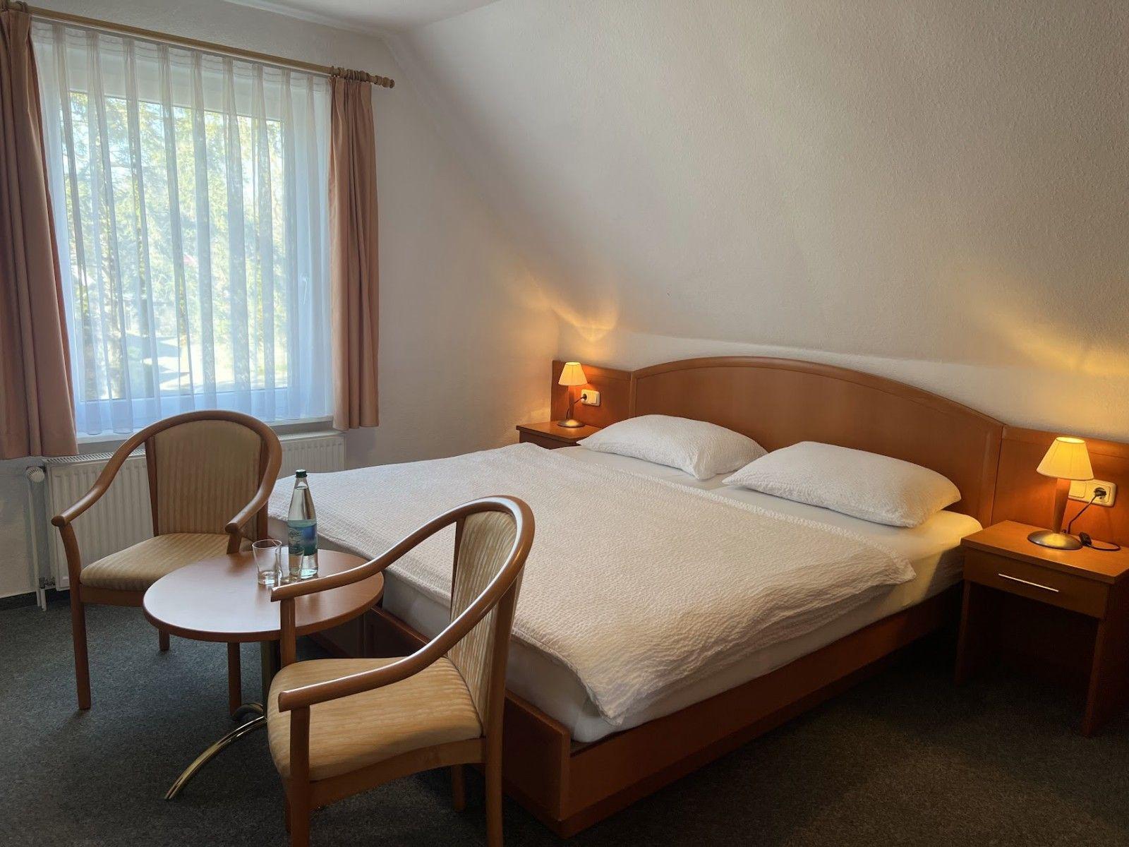 Ein Schlafzimmer mit Doppelbett, zwei Nachttischen, Stühlen und einem Fenster.