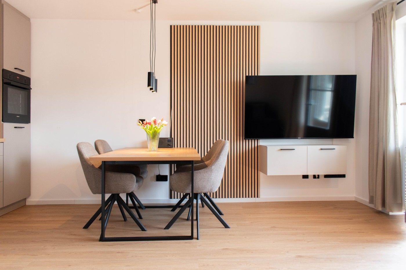 Essbereich mit Tisch, Stühlen und Fernseher an der Wand.