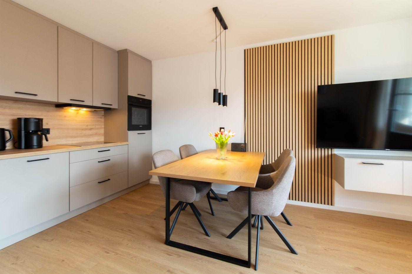 Moderne Küche mit Essbereich und Fernsehgerät an der Wand.