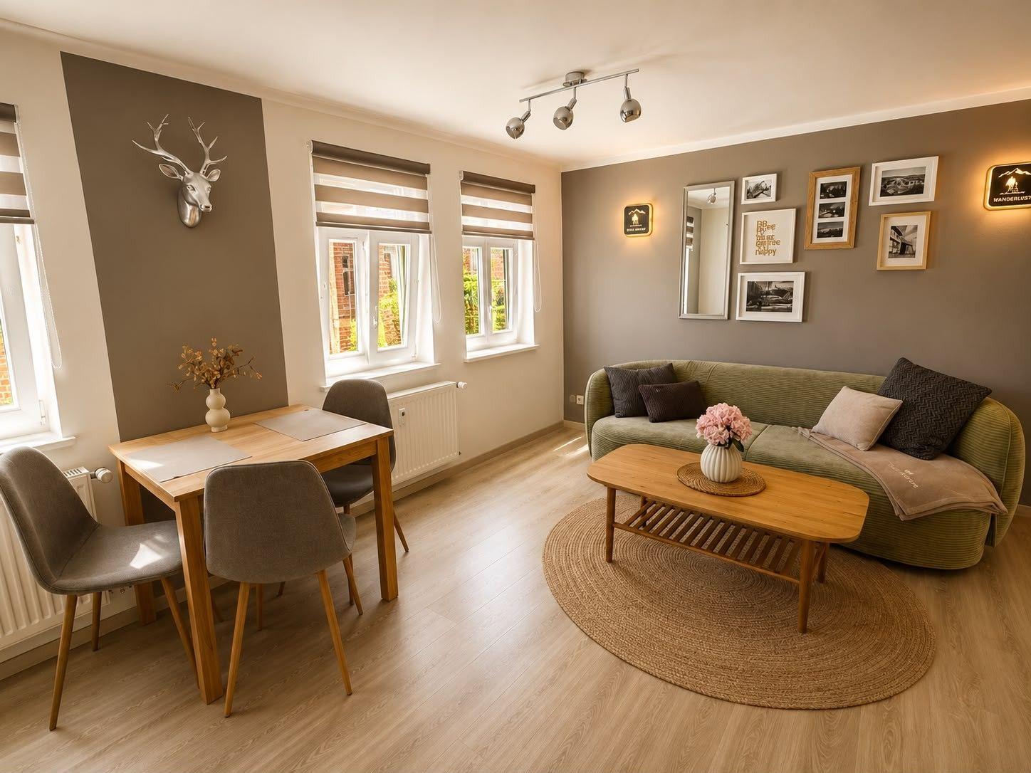 Wohn- und Essbereich mit Sofa, Tisch und Stühlen. Wand mit Hirschgeweih und Bildern.