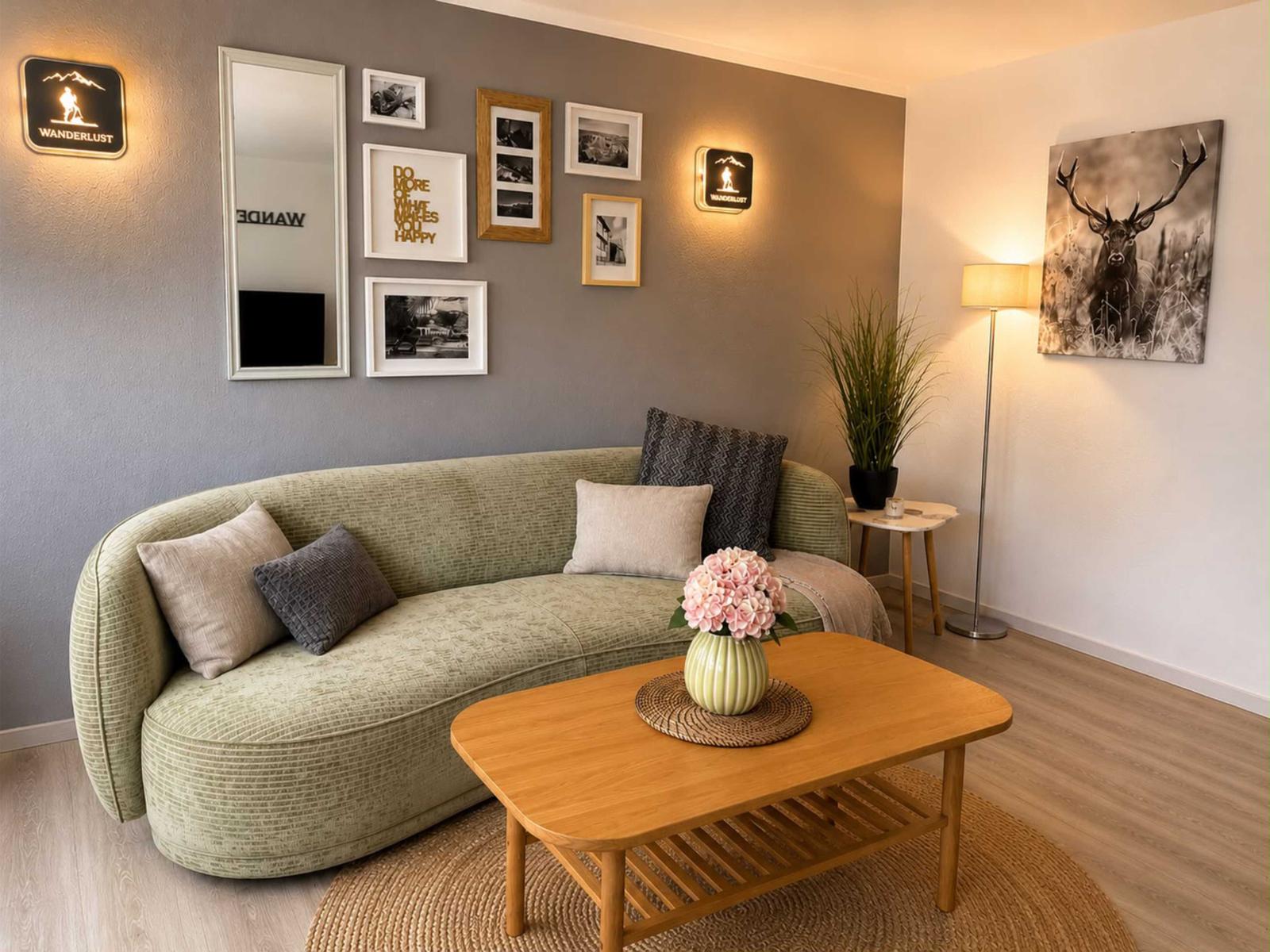 Ein Wohnzimmer mit grünem Sofa, Holztisch und Wanddekoration.