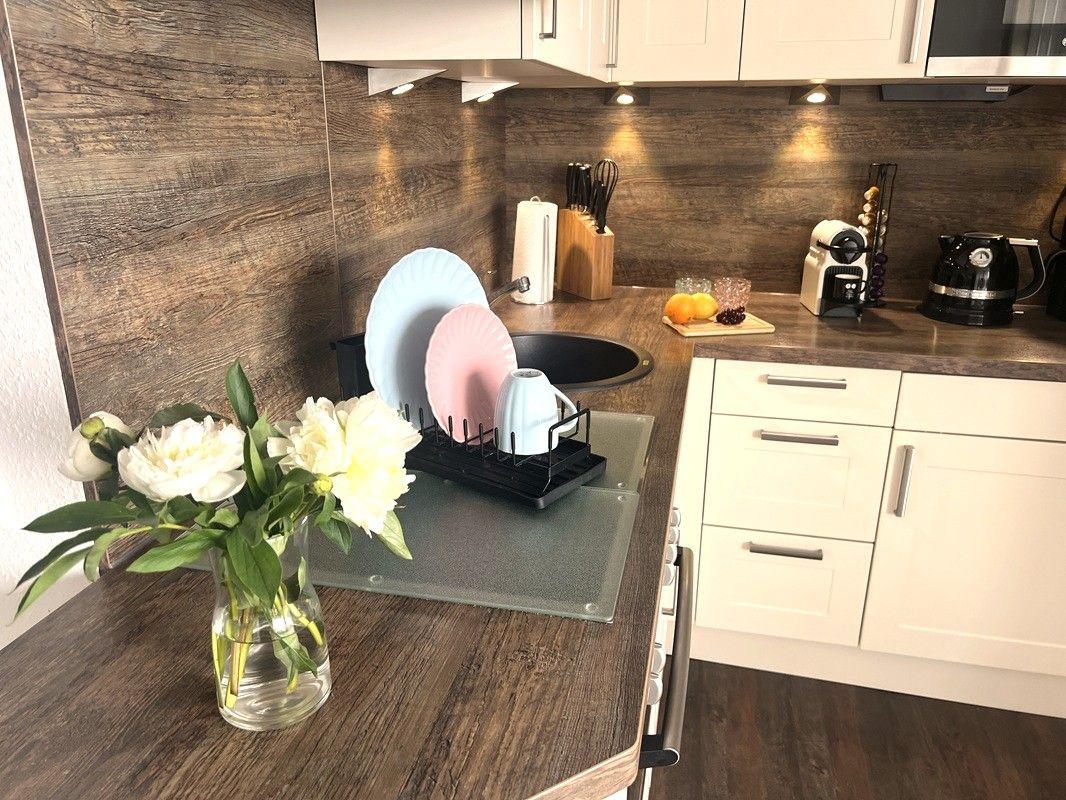 Kitchen with wood finish, sink, dishes, and flowers on the countertop.
