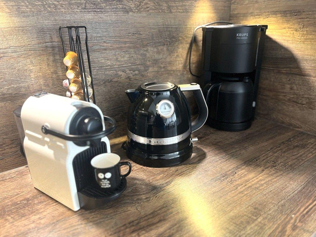 Coffee machine, kettle, and coffee maker on wooden surface.
