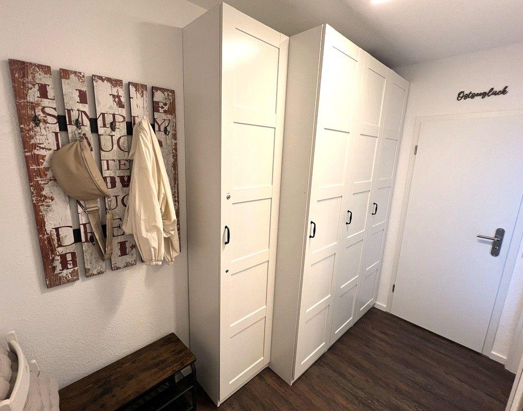 Hallway with white wardrobes, wall decor, and wooden bench