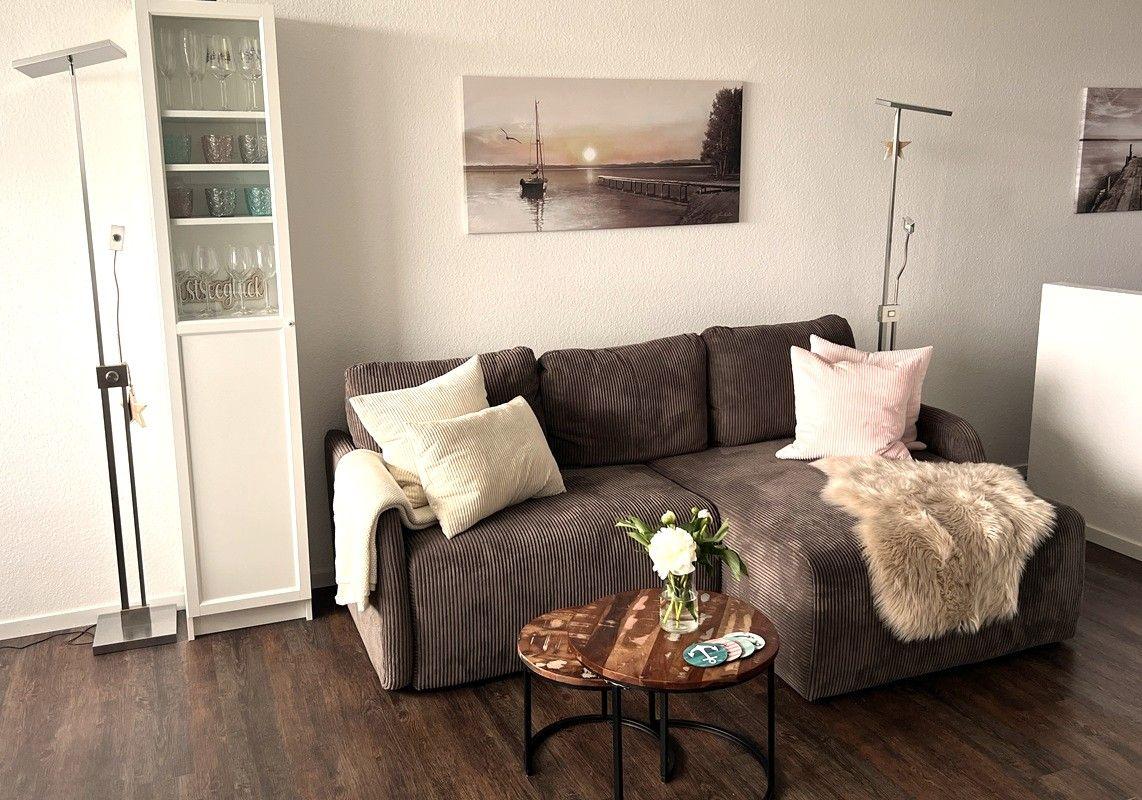 A living room with a brown sofa, decorative cushions, and a round table.