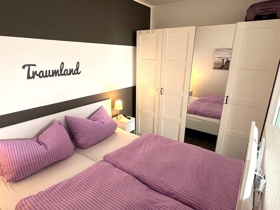 Bedroom with bed, wardrobe, and wall decoration.