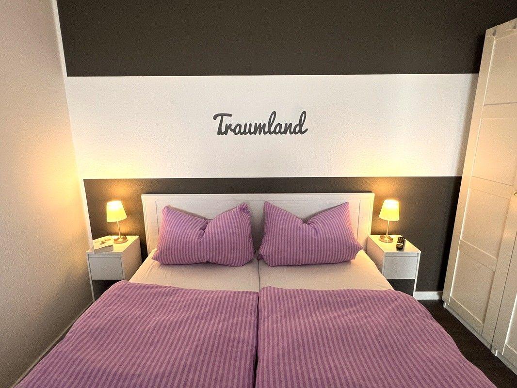 Bedroom with double bed, two nightstands, and wall decor.