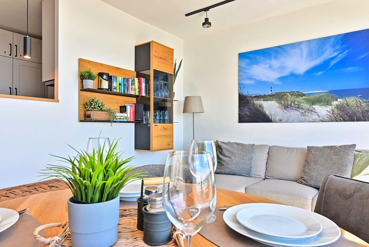 Ein Essbereich mit Tisch, Stühlen und einer Couch. An der Wand hängt ein großes Bild mit einem Leuchtturm.