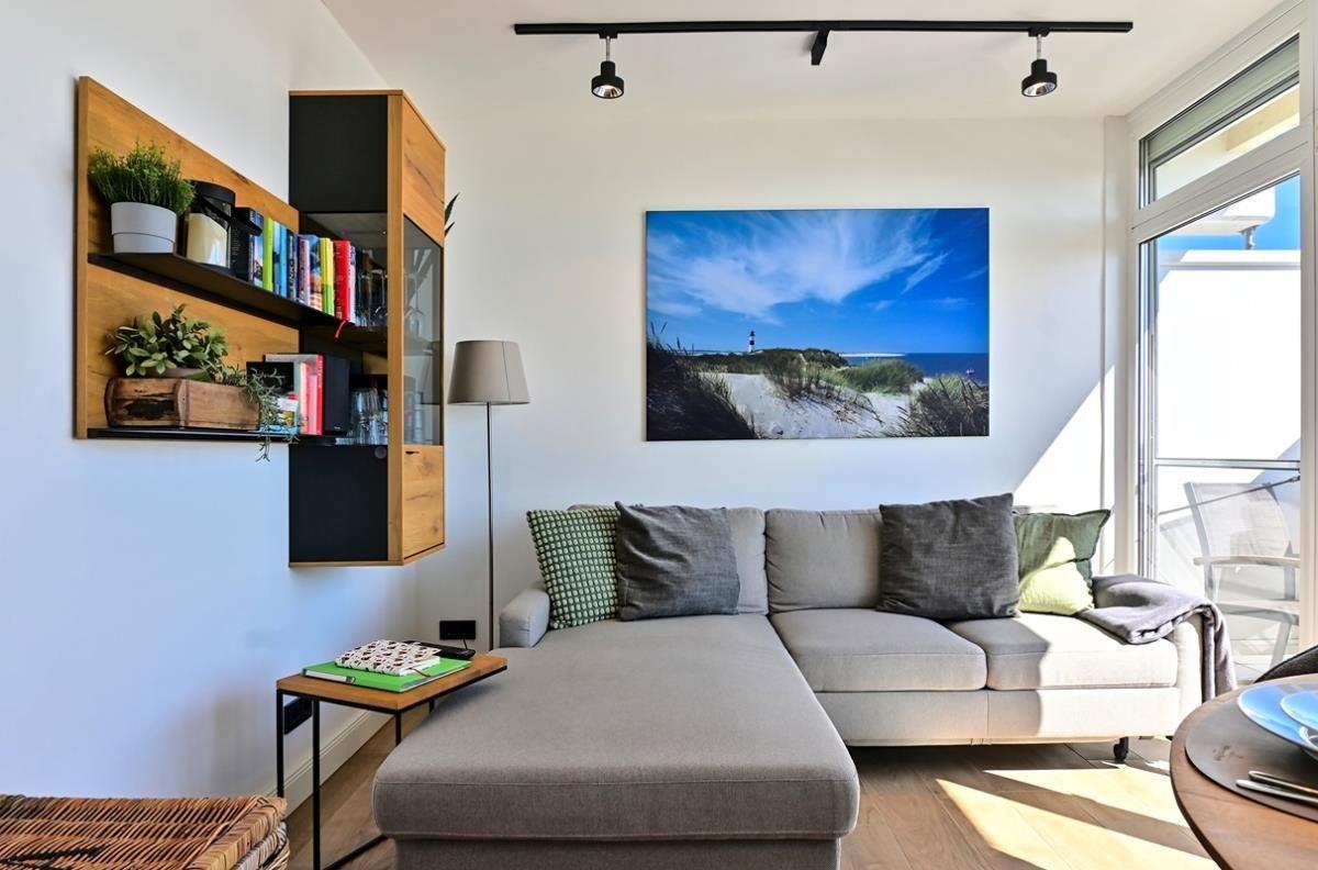 Wohnzimmer mit Sofa, Wandbild und Glasfront zum Balkon.