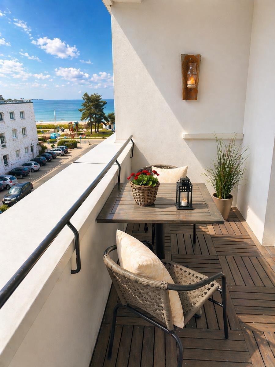 Balkon mit Tisch, Stühlen und Blick auf Strand und Meer.