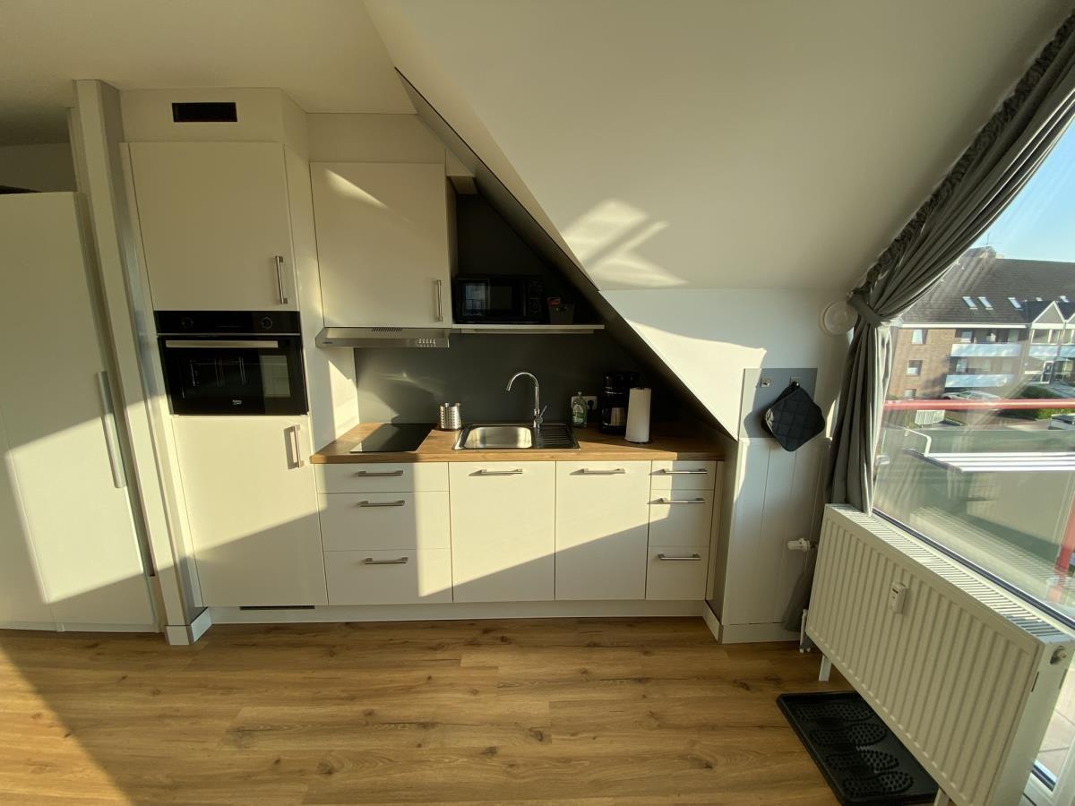 Küche mit weißen Schränken, Holz Arbeitsplatte und Fenster mit Blick.