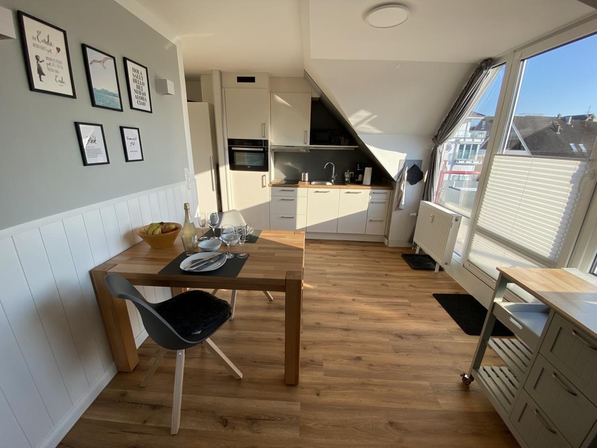 Küche mit Esstisch, Fenster und Holzboden. Wand mit Bildern.