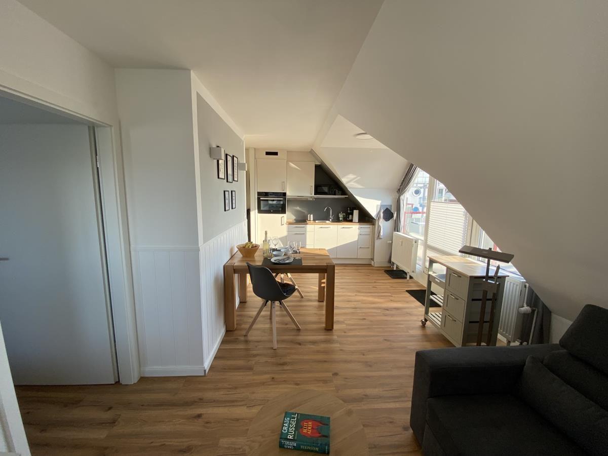Wohnung mit Essbereich, Küche und Sofa unter Dachschrägen.