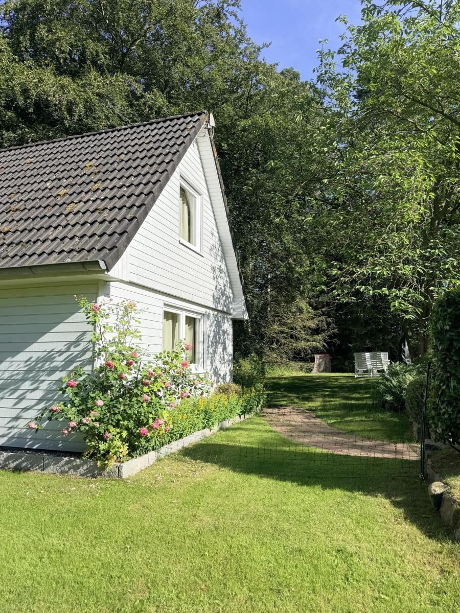 Wohnhaus mit Gartenterrasse und Blumenbeet im Grünen.