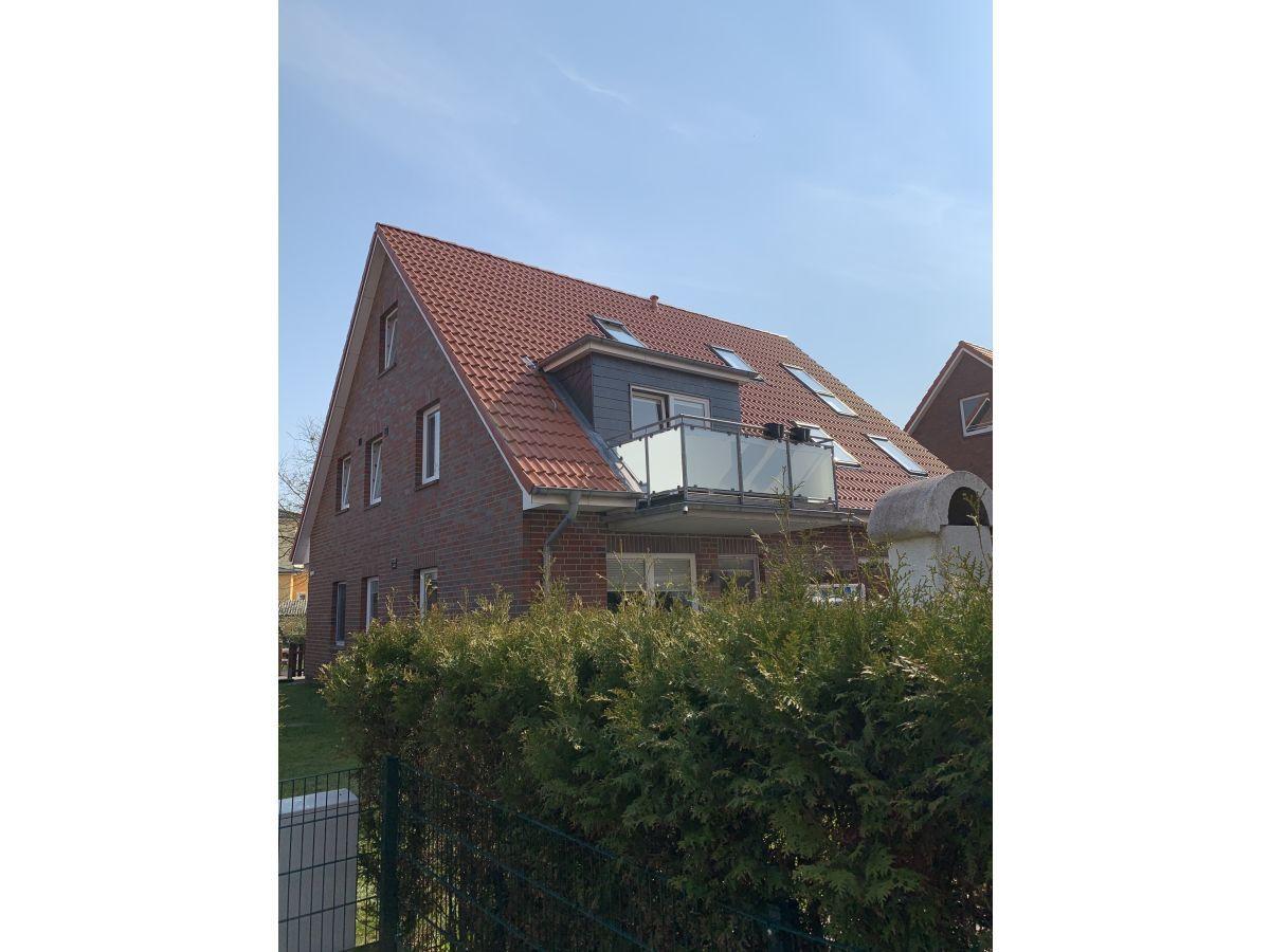 Modernes Haus mit Balkon und Dachfenstern. Grüner Garten im Vordergrund.