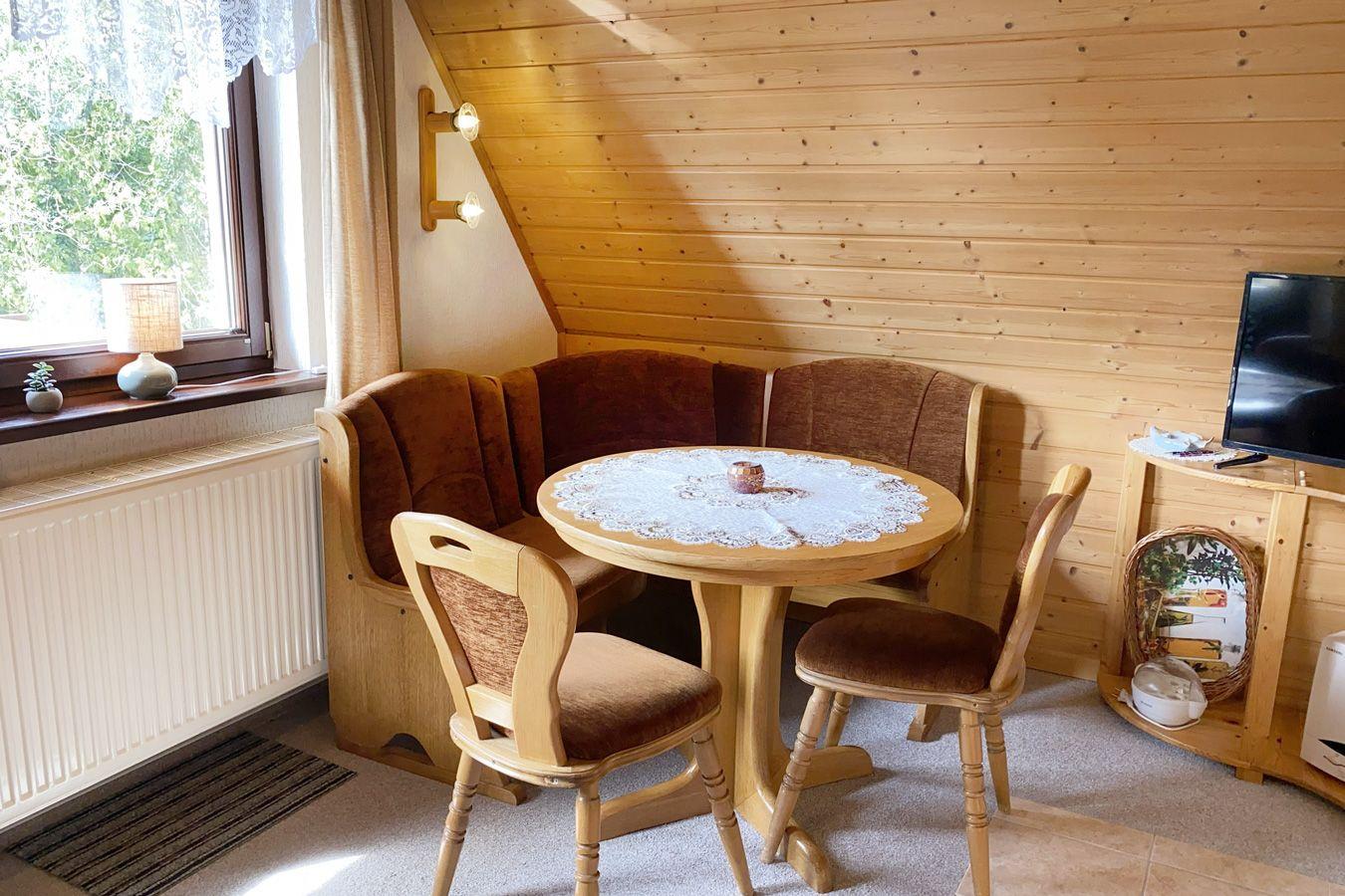 Dining area with wooden table, chairs, and bench by window with wood wall